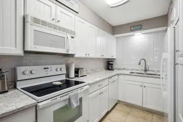 kitchen featuring white cabinets, white appliances, light stone counters, and sink