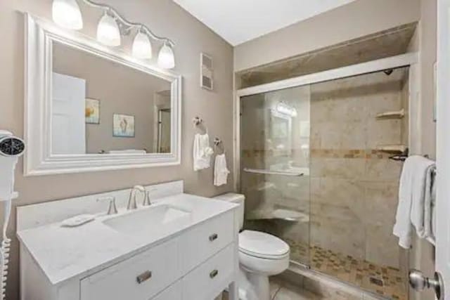 bathroom featuring vanity, toilet, and an enclosed shower