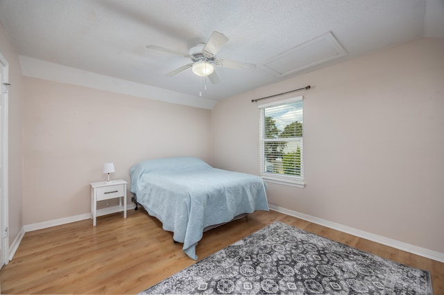 bedroom with a textured ceiling, vaulted ceiling, wood-type flooring, and ceiling fan