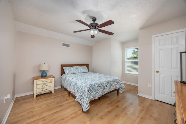 bedroom with ceiling fan, wood-type flooring, and a textured ceiling