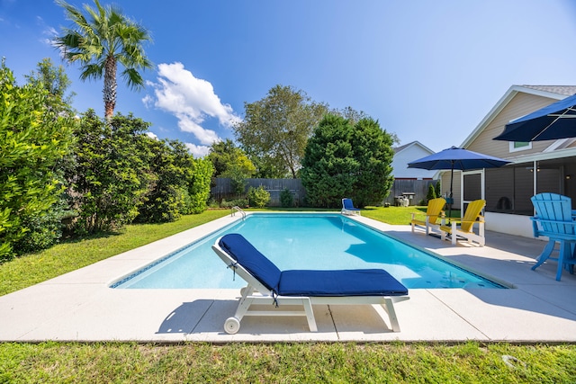 view of pool with a patio and a lawn