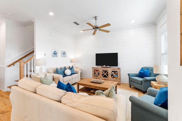 living room with light wood-type flooring, ceiling fan, and crown molding