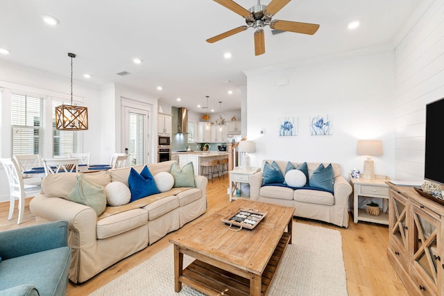 living room with light hardwood / wood-style floors, ceiling fan, and crown molding