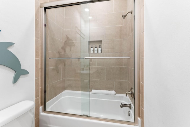 bathroom with combined bath / shower with glass door and toilet