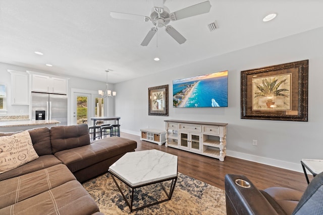 living room featuring ceiling fan with notable chandelier and dark wood-type flooring