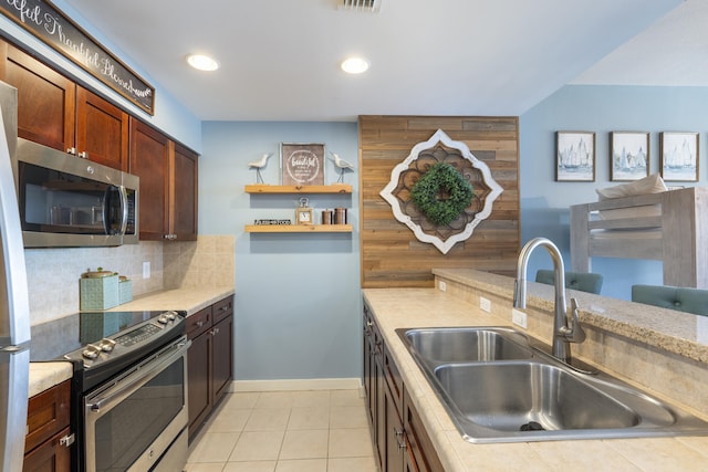 kitchen featuring decorative backsplash, appliances with stainless steel finishes, light tile patterned floors, and sink