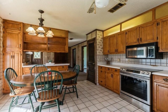 kitchen with light tile patterned floors, decorative light fixtures, backsplash, appliances with stainless steel finishes, and ceiling fan with notable chandelier