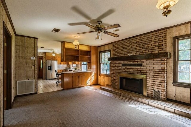 unfurnished living room featuring a brick fireplace, wooden walls, and a textured ceiling