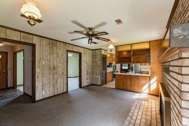 kitchen featuring ceiling fan, stainless steel range oven, kitchen peninsula, ornamental molding, and carpet flooring