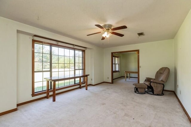 living area featuring ceiling fan and light colored carpet