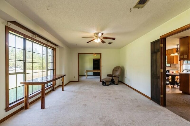 interior space with light colored carpet, a textured ceiling, and ceiling fan with notable chandelier