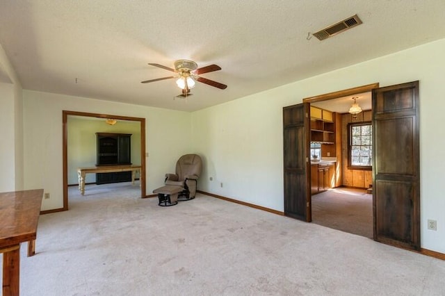 unfurnished room with light carpet, ceiling fan, and a textured ceiling