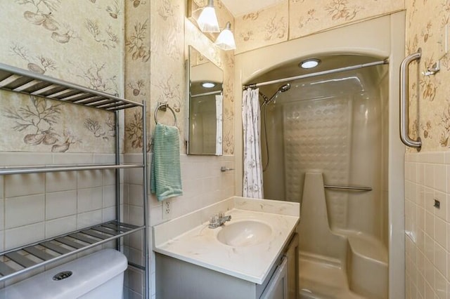 bathroom featuring vanity, walk in shower, toilet, and tile walls