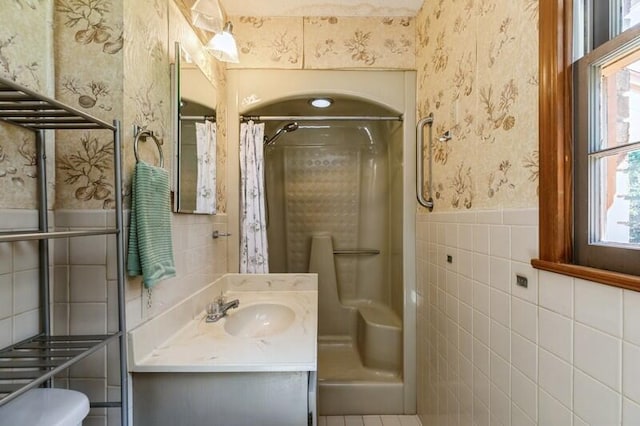 bathroom featuring walk in shower, tile walls, vanity, and toilet