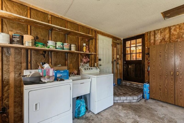 laundry room featuring independent washer and dryer, wood walls, and a textured ceiling