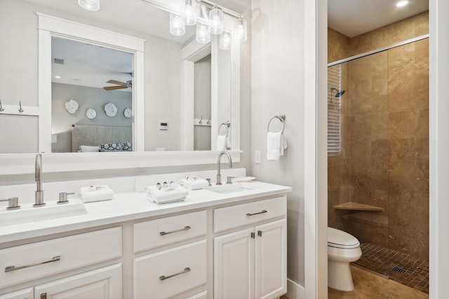 bathroom featuring ceiling fan, vanity, tiled shower, tile patterned floors, and toilet