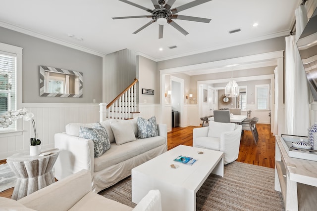 living room with ceiling fan with notable chandelier, crown molding, and hardwood / wood-style floors