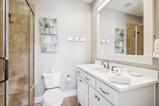 bathroom featuring vanity, a shower with shower door, and toilet