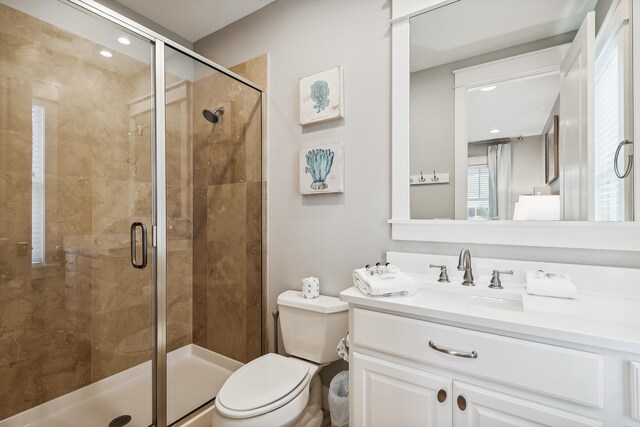 bathroom featuring vanity, toilet, and a shower with door