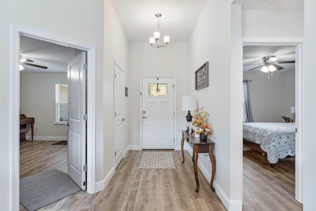 entryway with light hardwood / wood-style floors and ceiling fan with notable chandelier