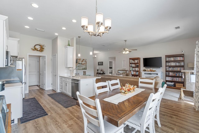 dining room featuring sink, ceiling fan with notable chandelier, and light wood-type flooring