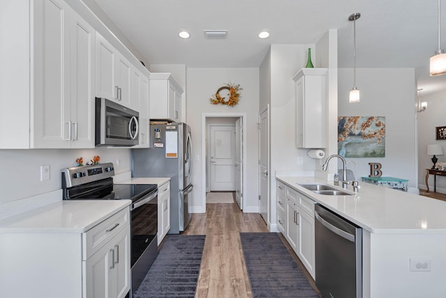 kitchen with white cabinets, stainless steel appliances, dark wood-type flooring, sink, and decorative light fixtures