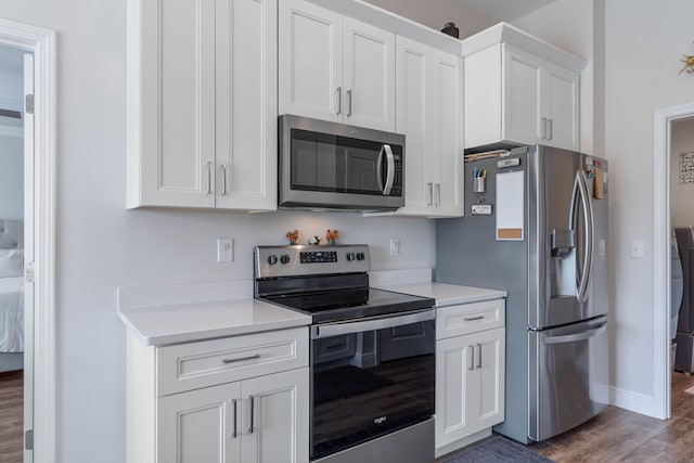 kitchen with white cabinetry, stainless steel appliances, and dark hardwood / wood-style flooring