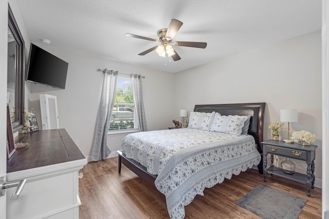 bedroom featuring dark wood-type flooring, ceiling fan, and a textured ceiling