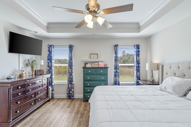 bedroom featuring ornamental molding, a tray ceiling, light hardwood / wood-style floors, and ceiling fan