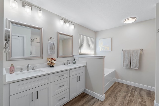 bathroom featuring vanity, wood-type flooring, a textured ceiling, and a bathing tub