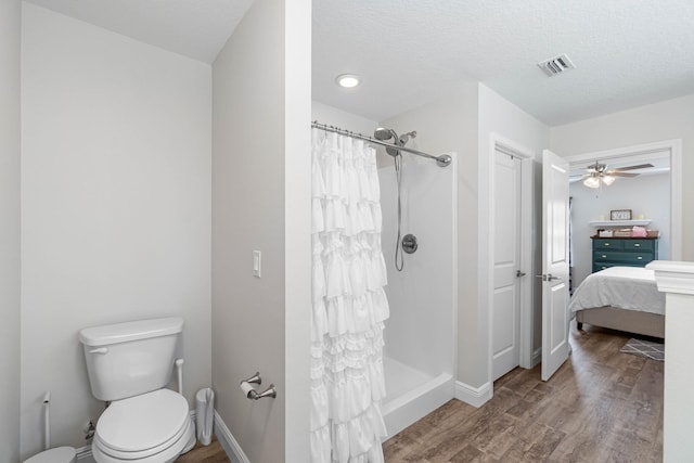 bathroom with curtained shower, wood-type flooring, toilet, and ceiling fan