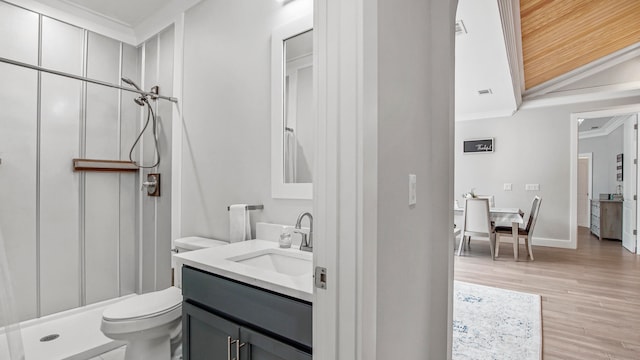 bathroom featuring vanity, walk in shower, hardwood / wood-style flooring, ornamental molding, and toilet