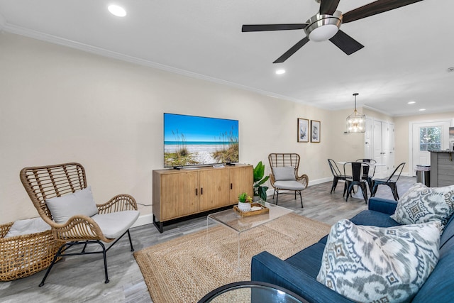 living room featuring ceiling fan with notable chandelier, light wood-type flooring, and crown molding