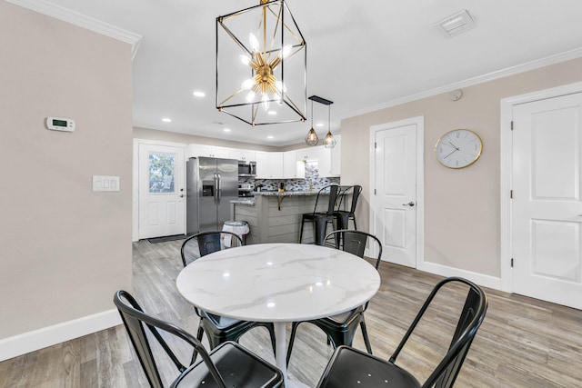 dining room featuring crown molding and light hardwood / wood-style flooring