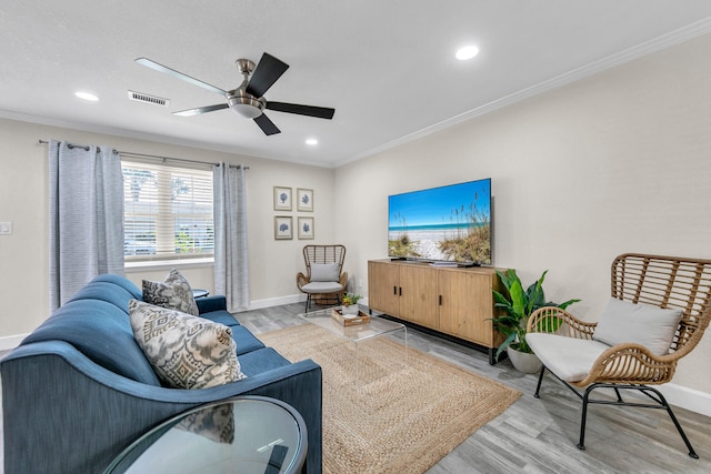 living room featuring ornamental molding, light hardwood / wood-style floors, and ceiling fan