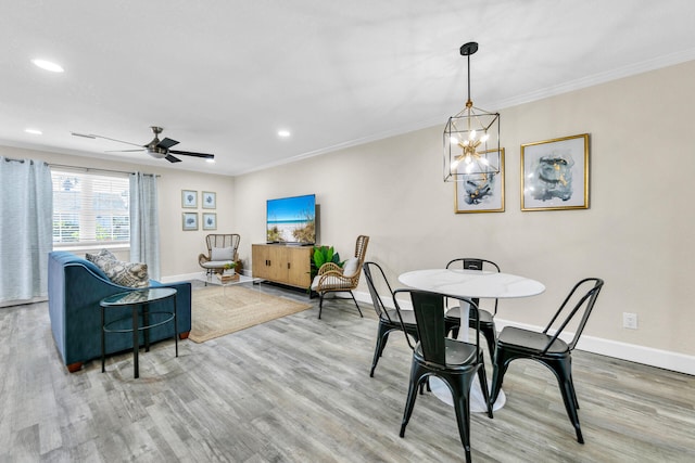 dining room with hardwood / wood-style flooring, ceiling fan with notable chandelier, and crown molding