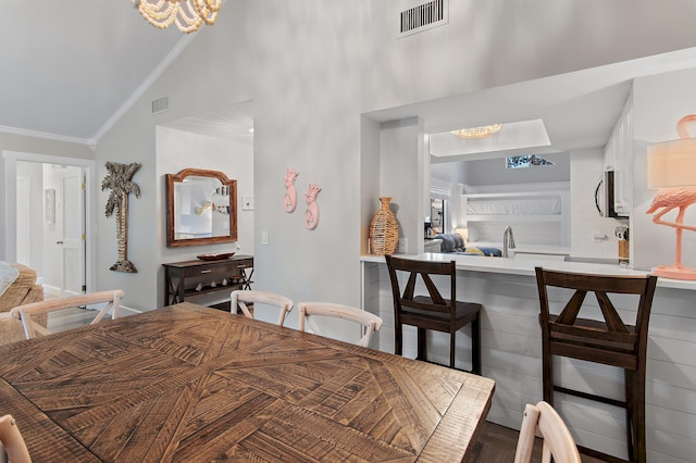 dining space with an inviting chandelier, crown molding, and high vaulted ceiling