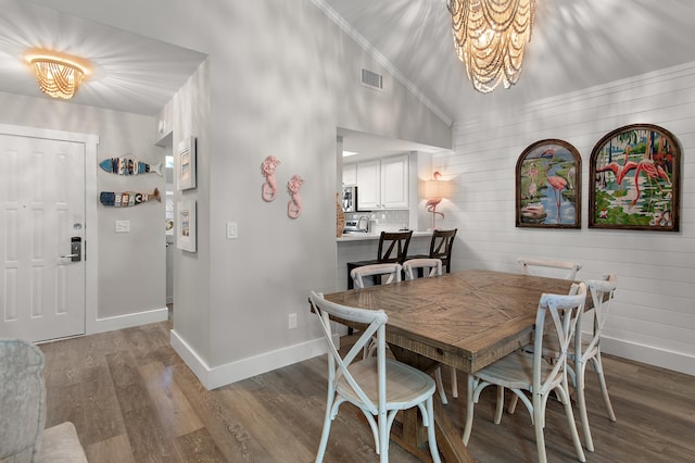 dining area featuring hardwood / wood-style flooring, wooden walls, crown molding, and high vaulted ceiling