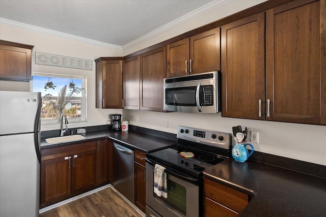 kitchen with appliances with stainless steel finishes, a textured ceiling, crown molding, sink, and dark hardwood / wood-style floors