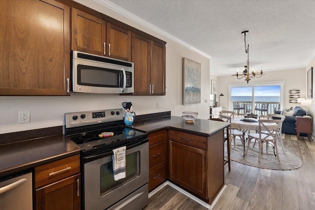 kitchen featuring a notable chandelier, kitchen peninsula, wood-type flooring, a textured ceiling, and appliances with stainless steel finishes