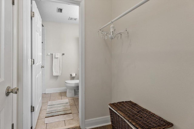 bathroom with tile patterned flooring, a textured ceiling, and toilet