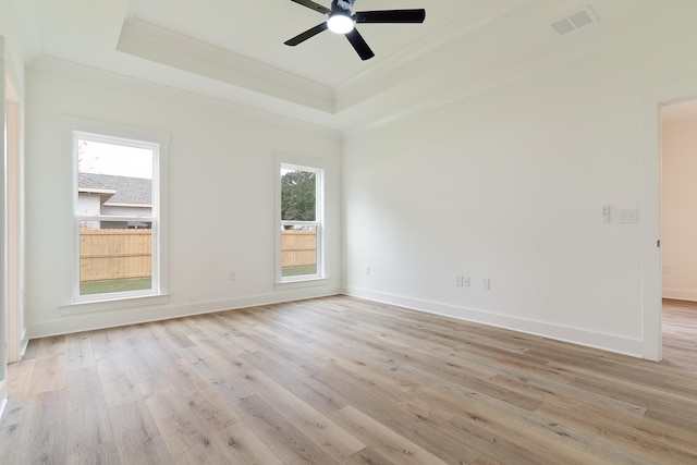 spare room with ceiling fan, a raised ceiling, and light hardwood / wood-style flooring