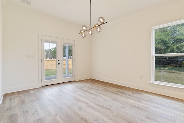 spare room featuring french doors, crown molding, a chandelier, and light hardwood / wood-style floors