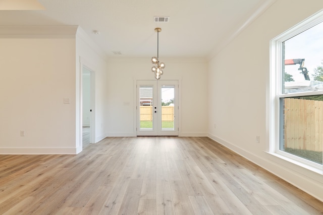 unfurnished room featuring crown molding, a chandelier, light wood-type flooring, and french doors