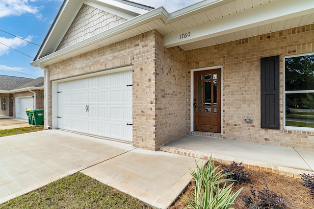 entrance to property with a garage, concrete driveway, and brick siding