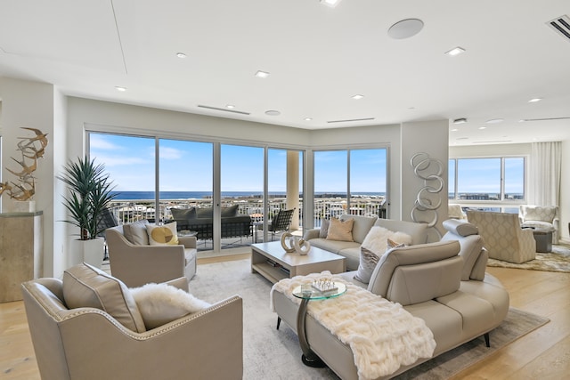 living room featuring light hardwood / wood-style flooring, a wealth of natural light, and a water view