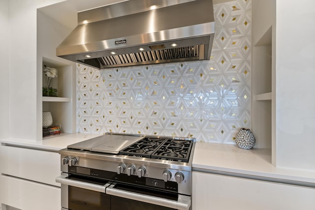 kitchen with wall chimney exhaust hood, gas range, and tasteful backsplash