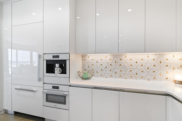 kitchen with white cabinets, backsplash, and oven