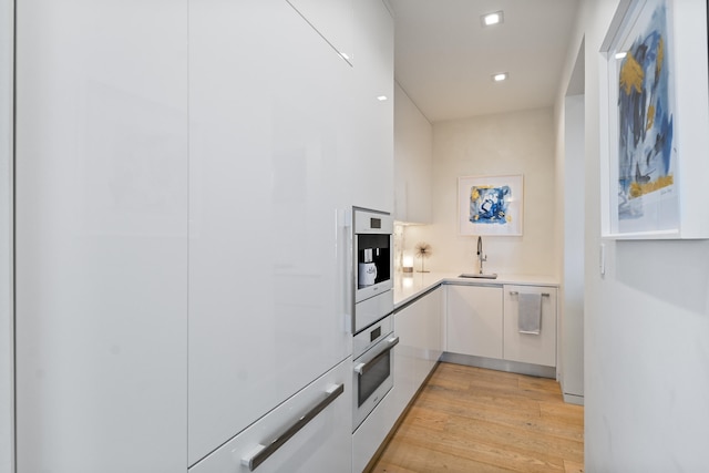 kitchen featuring light hardwood / wood-style floors, white appliances, sink, and white cabinets