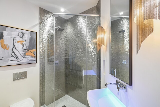 bathroom featuring a shower with shower door and toilet